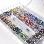 Clear organizer box with compartments filled with various colored rhinestones on a white background.