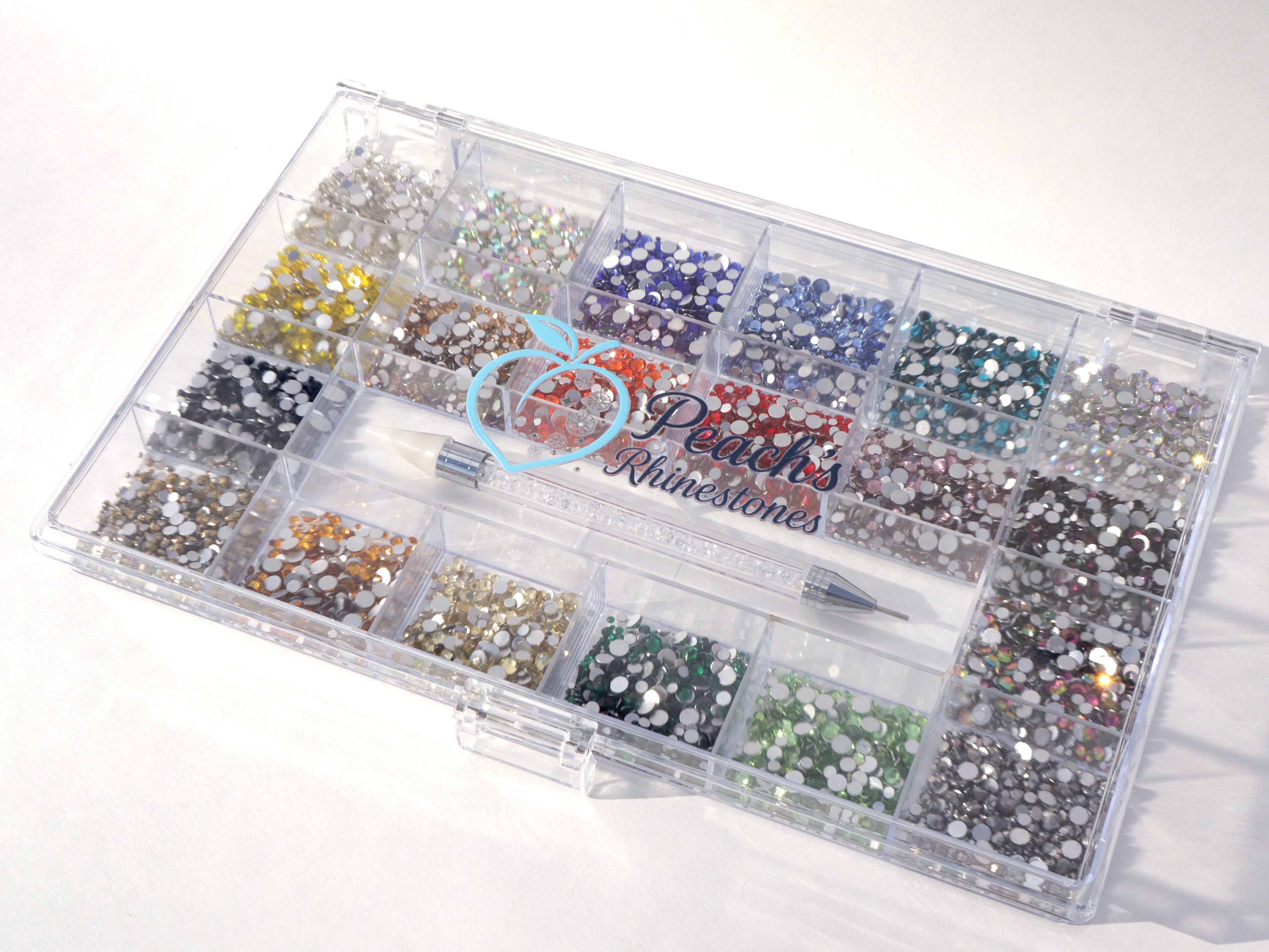 Clear organizer box with various sizes and colors of rhinestones on a white background.